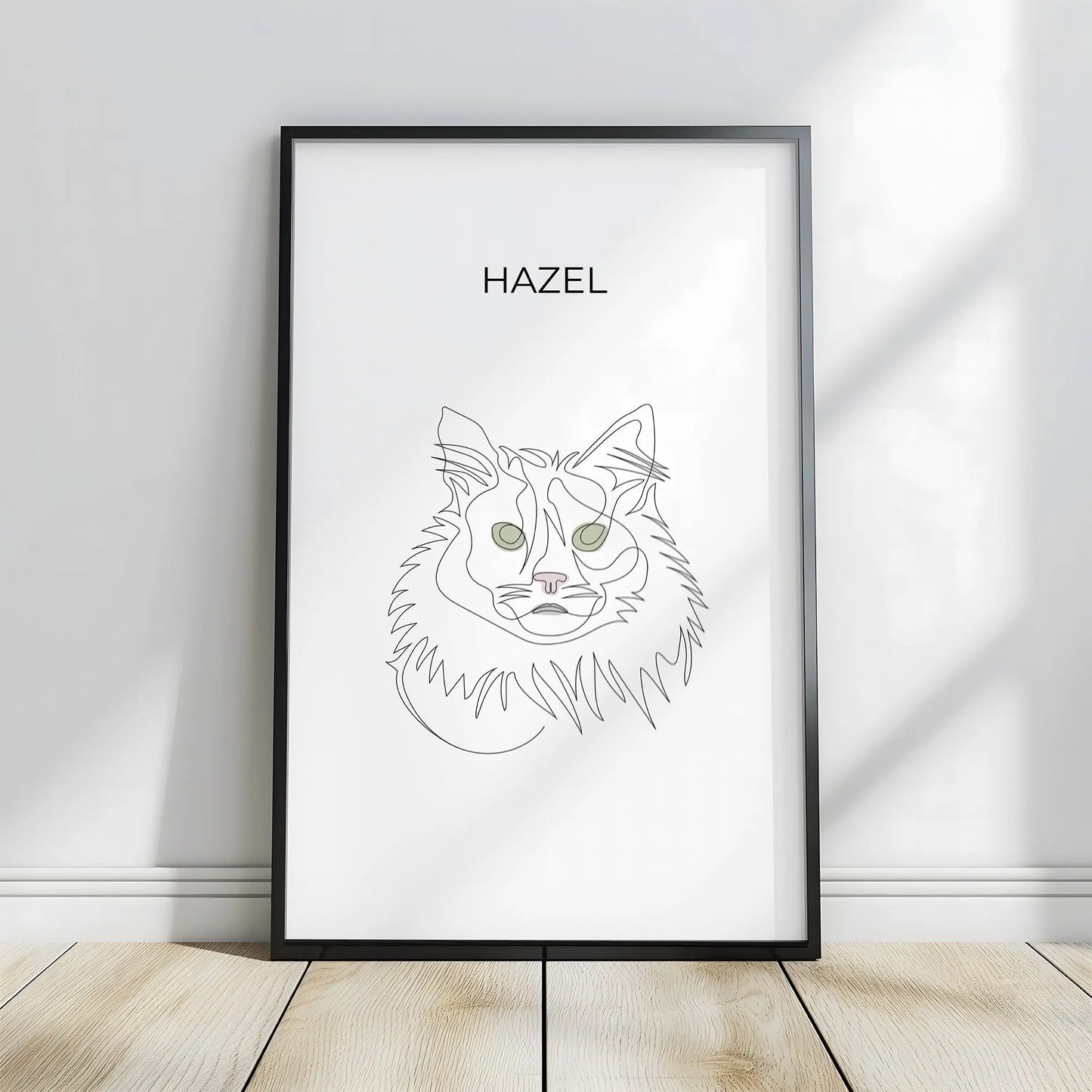 Minimalistisches One Line Art Katzenportrait mit Namen Hazel, individuelles Haustierportrait nach Fotovorlage im modernen Stil als Wandbild mit schwarzem Rahmen in 40x60cm frontal an einer weissen Wand lehnend.
