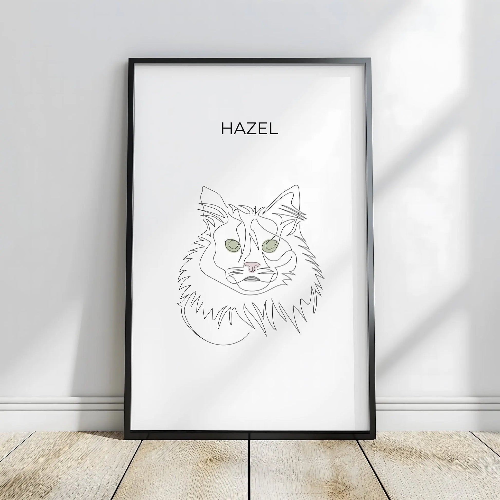 Minimalistisches One Line Art Katzenportrait mit Namen Hazel, individuelles Haustierportrait nach Fotovorlage im modernen Stil als Wandbild mit schwarzem Rahmen in 40x60cm frontal an einer weissen Wand lehnend.